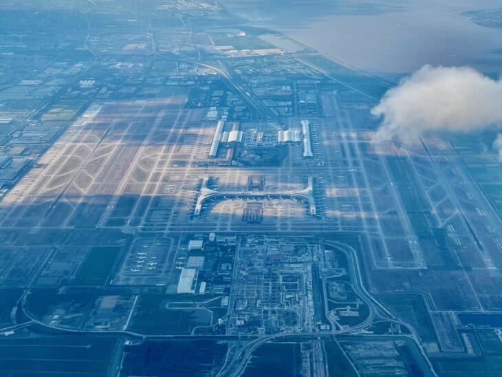 Aerial view of Shanghai Pudong International Airport, its long parallel runways and two terminals stretching toward the coast of the East China Sea