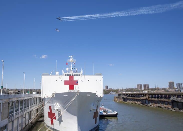 The hospital ship USNS Comfort docked on the Hudson River as the Blue Angels and Thunderbirds pass overhead trailing smoke