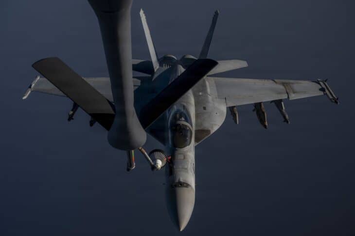 U.S. Navy F/A-18 Super Hornet with its probe in the basket of a drogue fitted to the KC-135 boom, dark sea below