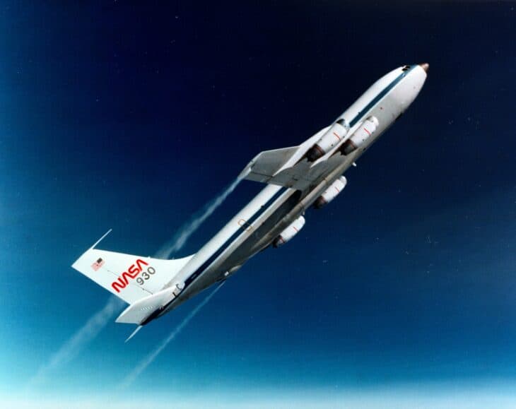 White and blue NASA KC-135A 930 climbing at a steep angle against a dark blue sky