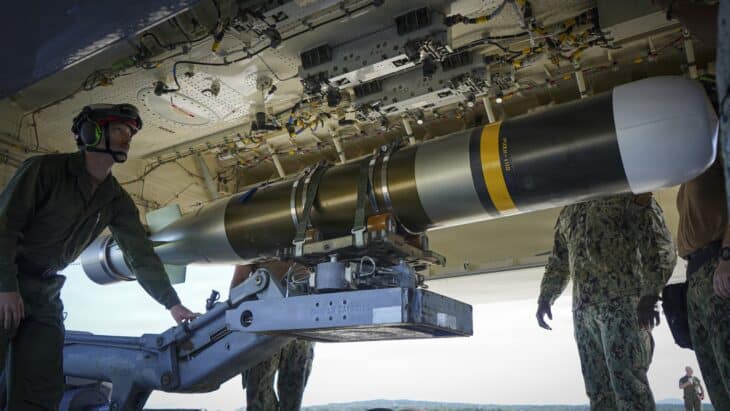 US Navy ordnance crew lifting a Mark 54 lightweight torpedo into the open weapons bay of a P-8A Poseidon