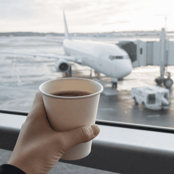 Holding the cup close to the lens keeps it sharp while the aircraft outside softens into context.