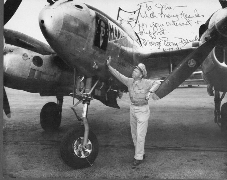 Richard Bong standing beside the nose of his P-38 Lightning, Marge
