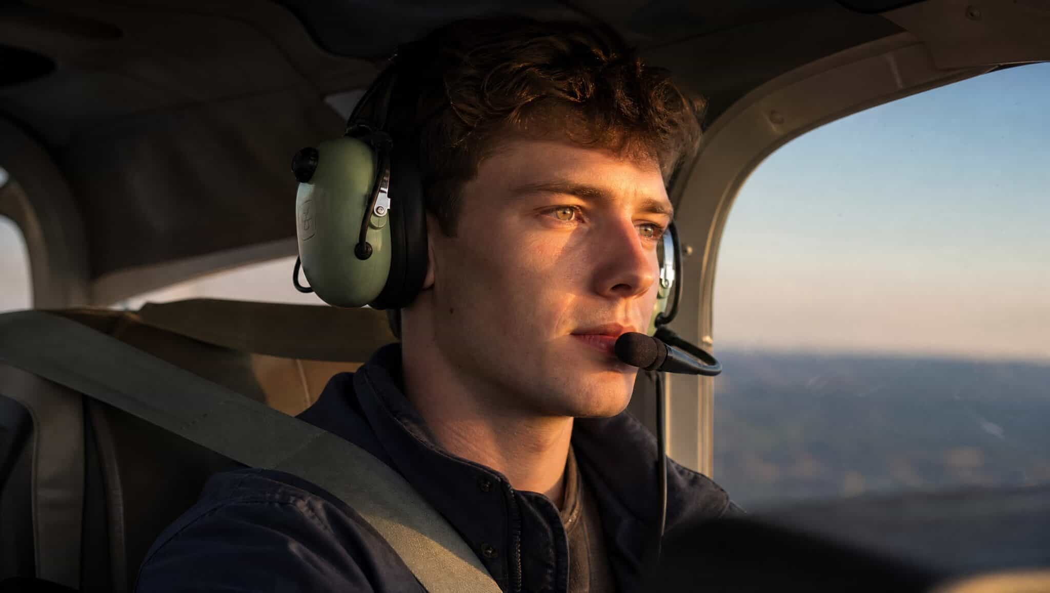 A student pilot in a headset at the controls of a small single-engine training airplane at sunset