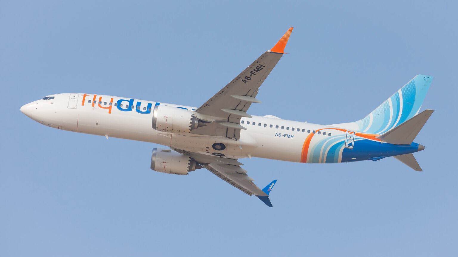 flydubai Boeing 737 MAX 8 A6-FMH banking after takeoff from Tel Aviv, seen from below against a gray sky