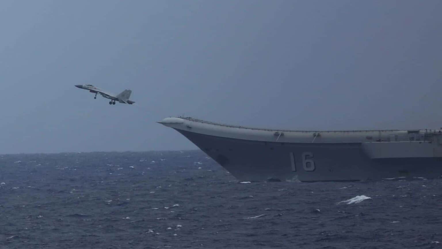 A Chinese J-15 fighter climbing away from the ski-jump bow of the carrier Liaoning, hull number 16, over a rough grey sea