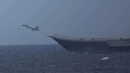 A Chinese J-15 fighter climbing away from the ski-jump bow of the carrier Liaoning, hull number 16, over a rough grey sea