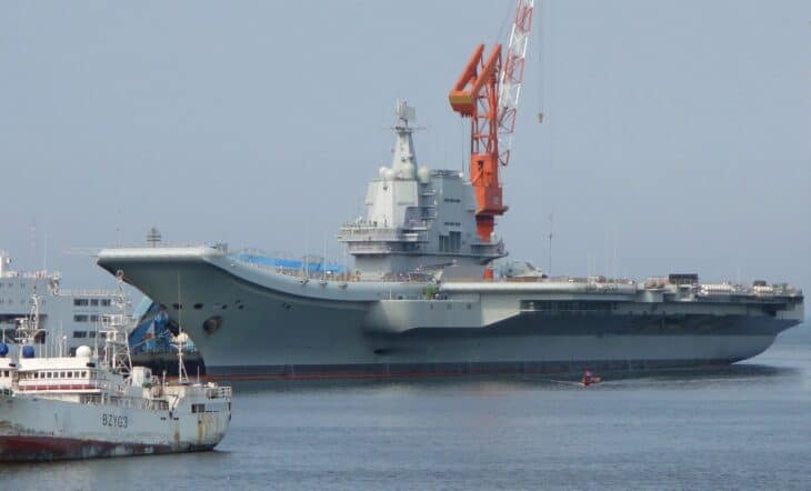 The Chinese aircraft carrier Shandong moored alongside with dockside cranes behind it