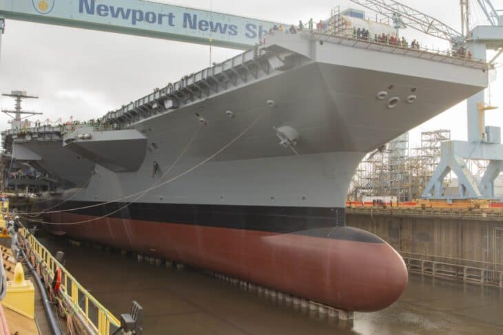 The Ford-class carrier USS John F. Kennedy (CVN-79) in dry dock at Newport News Shipbuilding with crowds on the deck edge