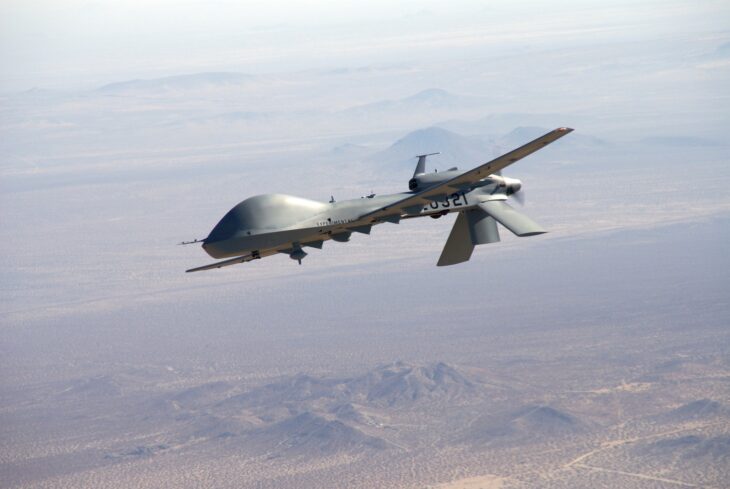 US Army MQ-1C Gray Eagle drone in flight over desert mountains