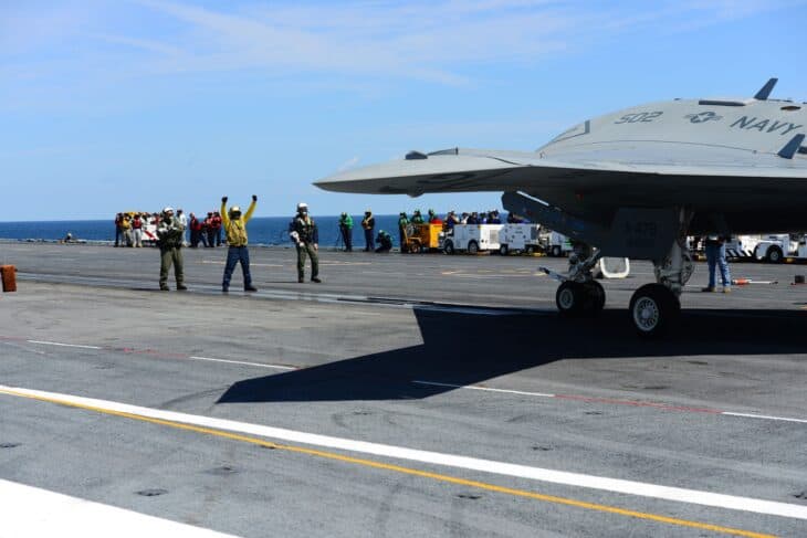 Navy flight deck crew directing an X-47B on the deck of an aircraft carrier