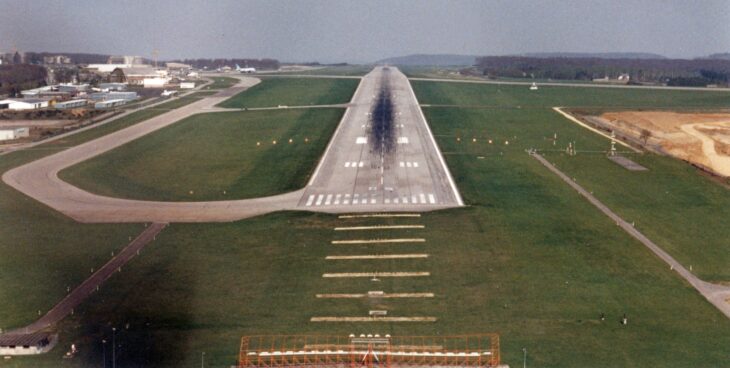 Aerial view along the single runway at Luxembourg-Findel airport, with taxiways and approach lights in the foreground