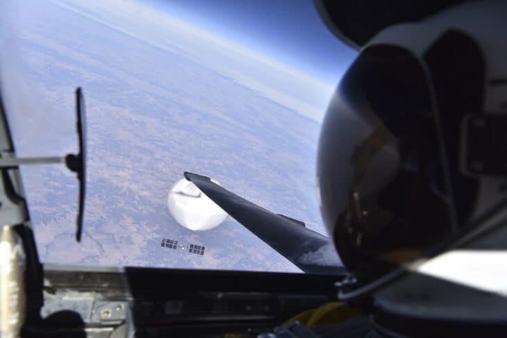 View from a U-2 cockpit showing the pilot's helmet and the white Chinese surveillance balloon with its payload far below