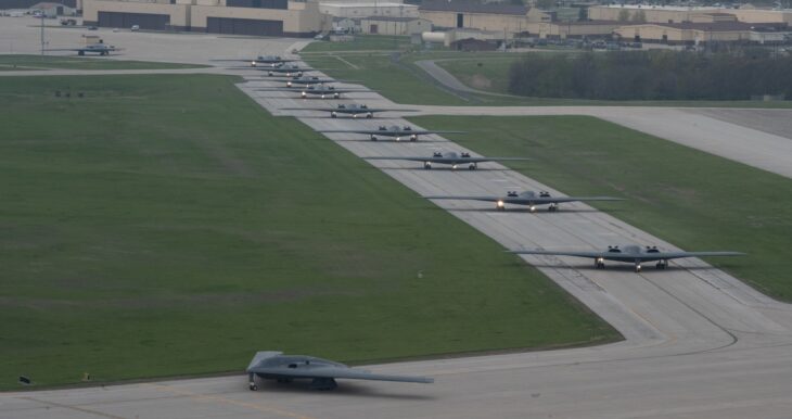A line of B-2 Spirit bombers taxiing nose to tail along a taxiway at Whiteman Air Force Base, Missouri