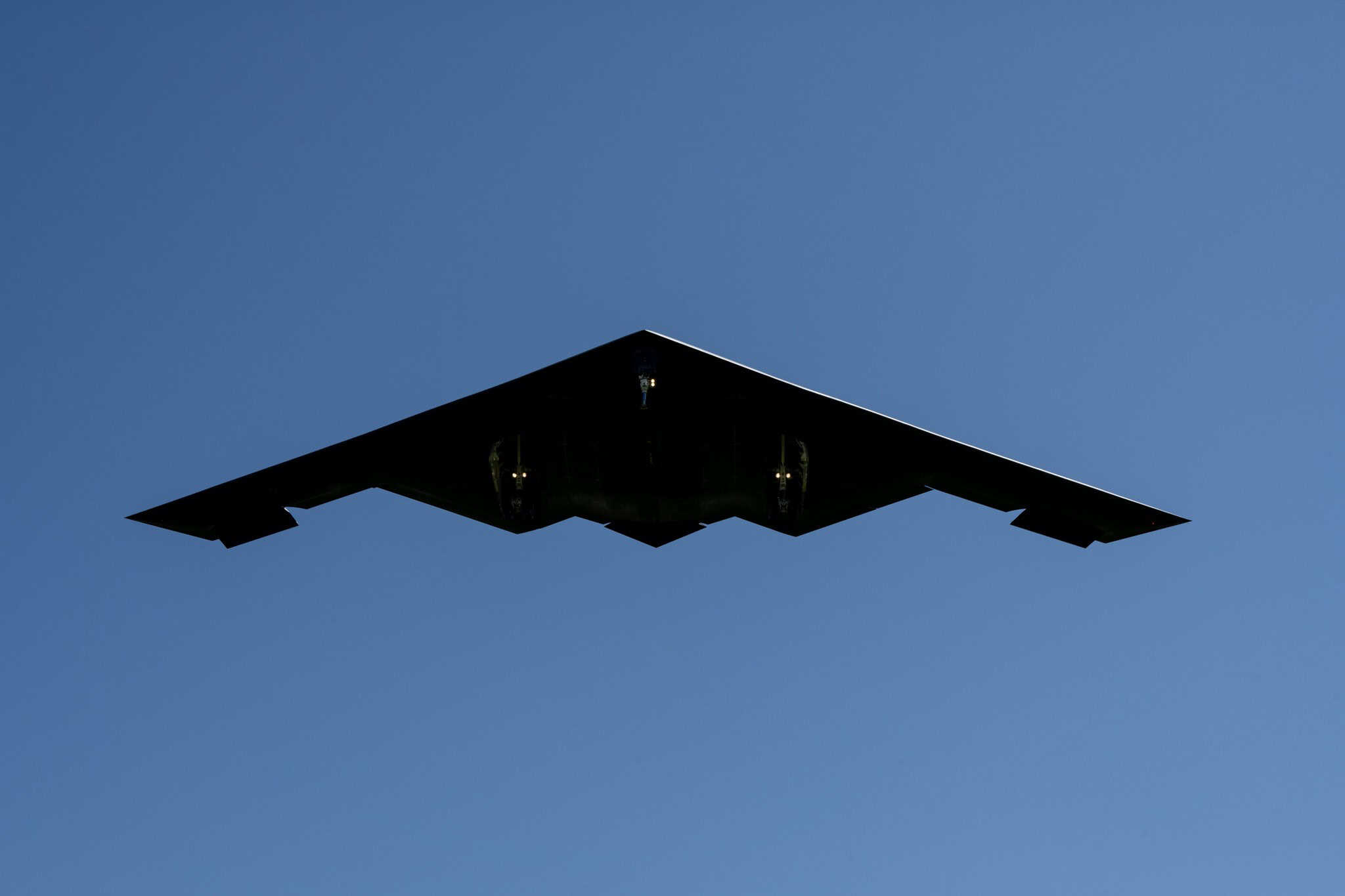 B-2 Spirit stealth bomber seen from below against a clear blue sky