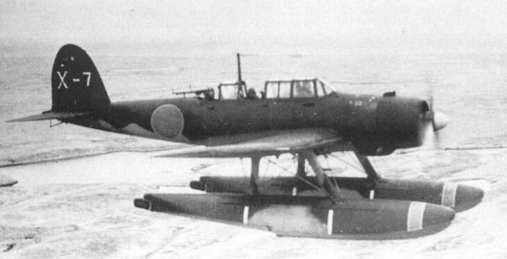 An Aichi E13A Jake three-seat reconnaissance floatplane in flight over the sea, tail code X-7