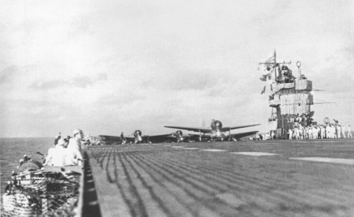 Crew on the carrier Akagi watch as second-wave aircraft line up and take off from the flight deck