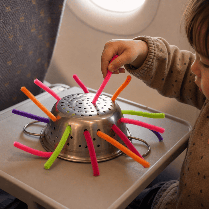 Threading pipe cleaners through a strainer is fine motor practice disguised as a game.