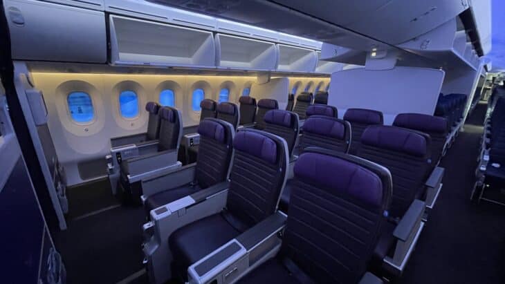 Rows of dark leather United Premium Plus seats with purple headrests, two by the window and three in the center, in a Boeing 787 cabin
