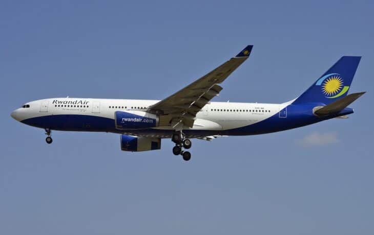 RwandAir Airbus A330-200 9XR-WN in flight with its landing gear down against a blue sky