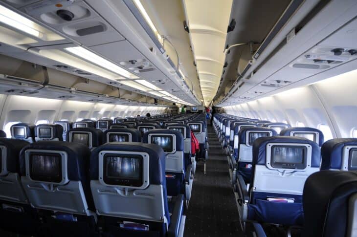 Long wide-body economy cabin seen down one aisle, seatback screens stretching toward the rear