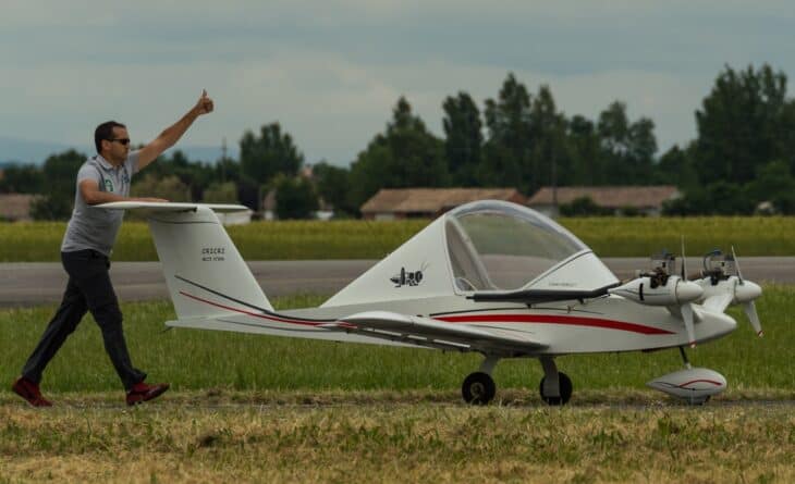 White Colomban Cri-Cri on the grass at AirExpo 2015 with a man walking beside it