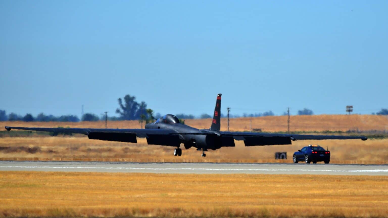 Black TU-2S Dragon Lady touching down at Beale Air Force Base with a chase car racing behind it on the runway