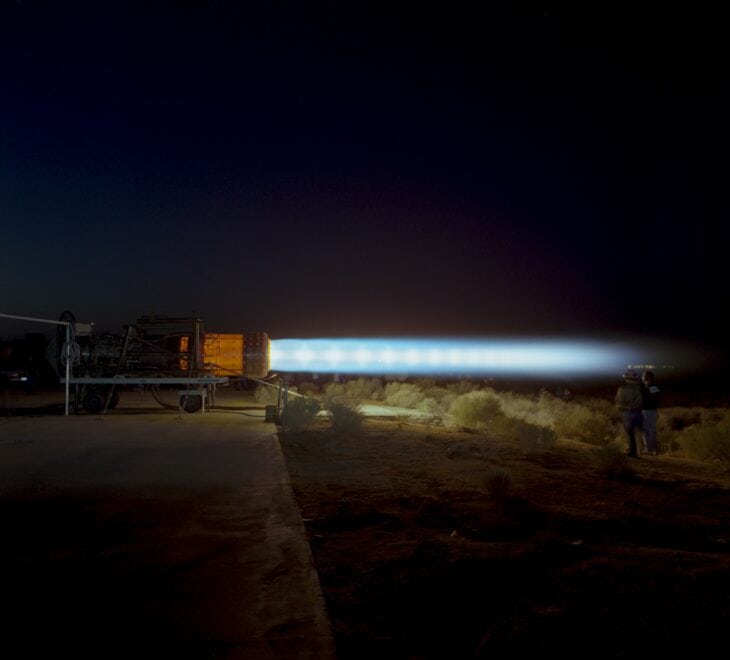 Pratt & Whitney J58 engine anchored to a test stand at night, running in full afterburner with a long glowing exhaust plume