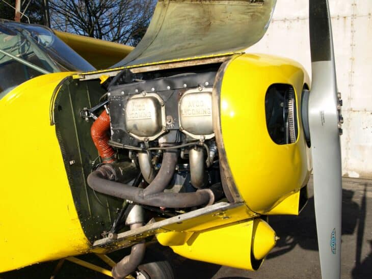 Lycoming O-360 four-cylinder horizontally opposed engine inside the open cowling of a yellow light aircraft, behind the propeller