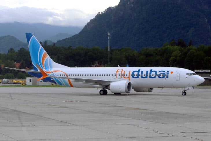 A flydubai Boeing 737 MAX 8, registration A6-FMO, on the apron at Salzburg Airport with forested mountains behind