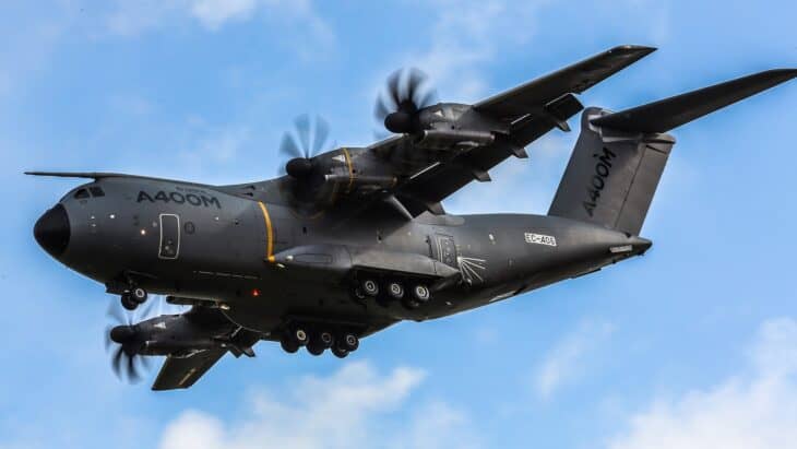 Dark gray Airbus A400M Atlas transport banking against blue sky with four propellers turning