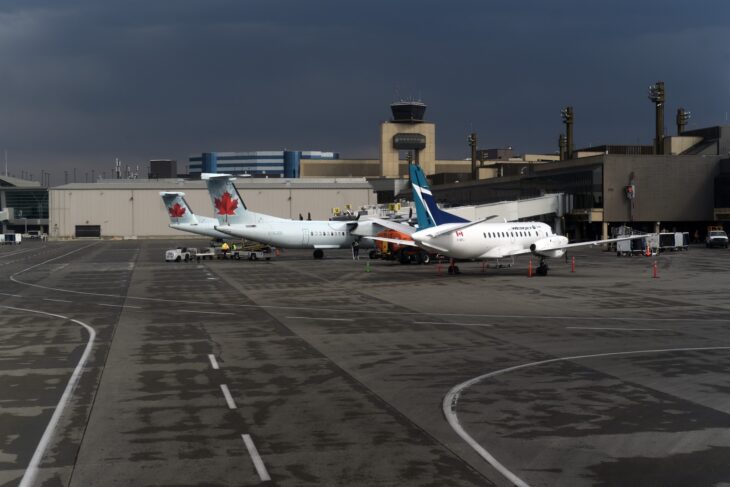 Air Canada Express and WestJet aircraft parked on the apron at Calgary International Airport beneath the control tower
