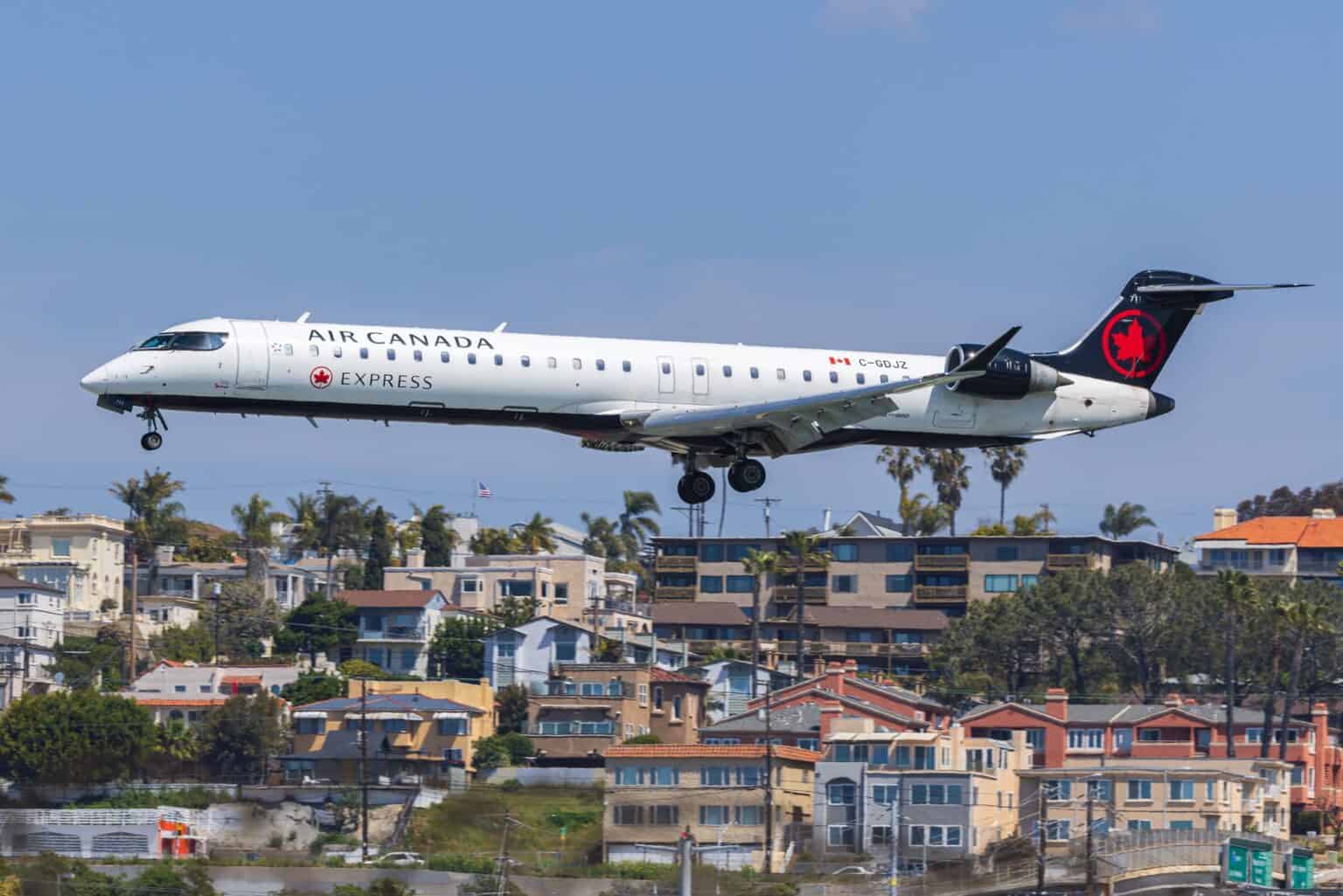 Air Canada Express Bombardier CRJ900 on final approach to San Diego over hillside homes