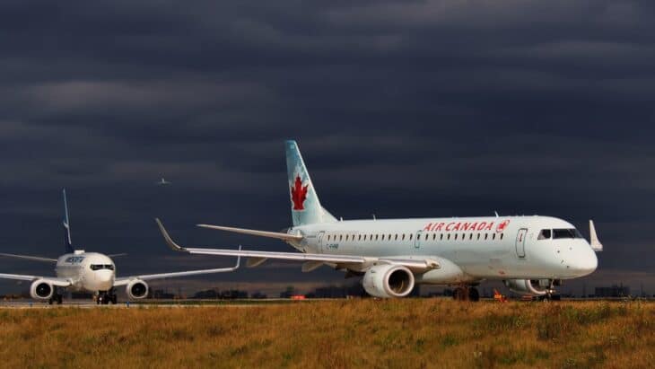 Air Canada Embraer E190 taxiing under a dark stormy sky at Toronto Pearson with a WestJet Boeing 737 behind it