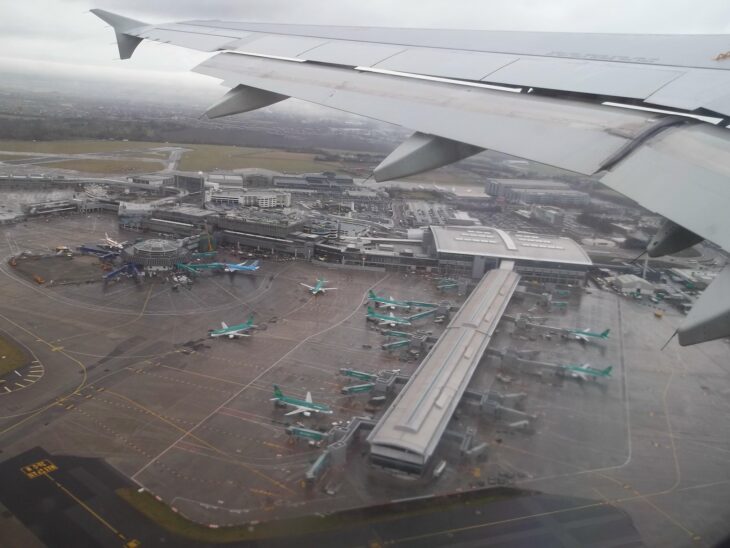 Aerial view of Dublin Airport terminals, piers and parked aircraft from an aircraft wing