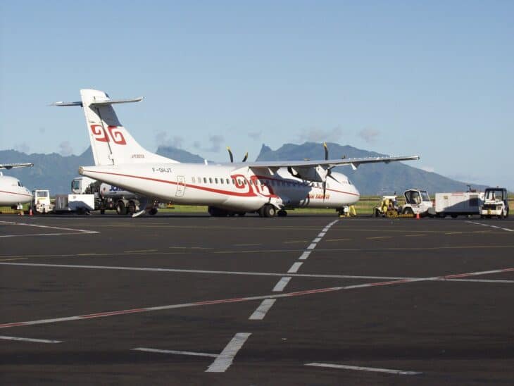 Air Tahiti ATR turboprop parked on the apron at Faa'a International Airport with Tahiti's mountains behind