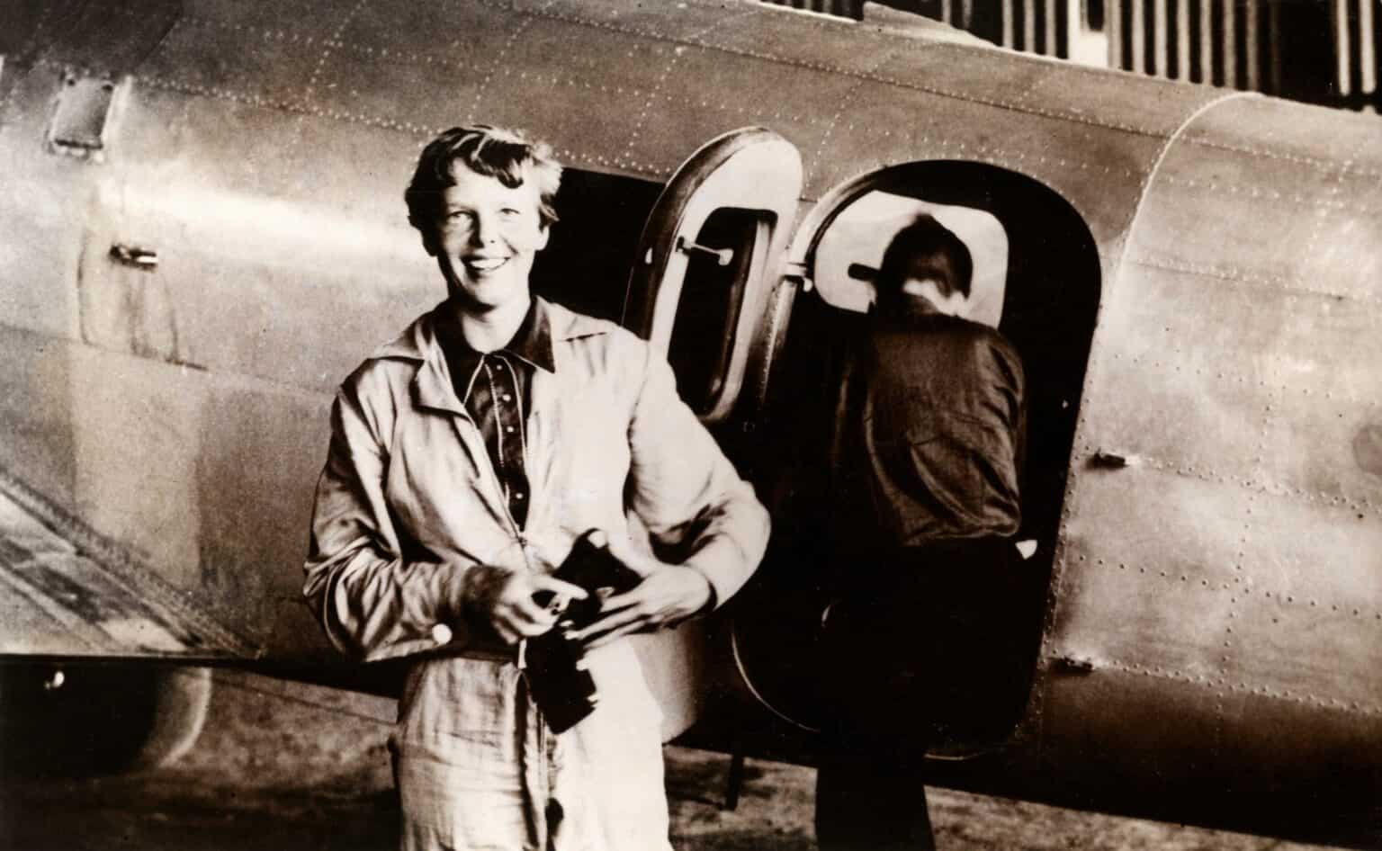 Amelia Earhart smiling beside the open door of her Lockheed Electra 10E