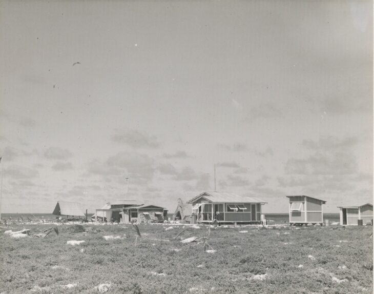 Low wooden buildings of the colonists' camp on flat, treeless Howland Island in 1937