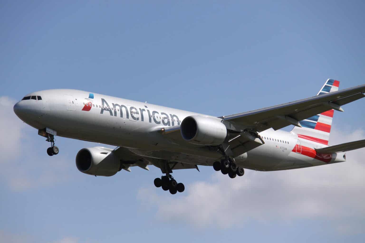 American Airlines Boeing 777-200ER N772AN on final approach with landing gear down against a blue sky