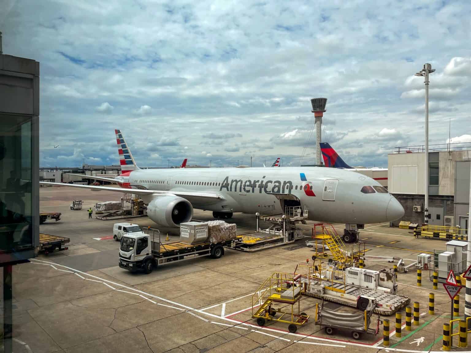 American Airlines Boeing 787-9 N827AN parked at a gate at London Heathrow Airport with ground service vehicles alongside
