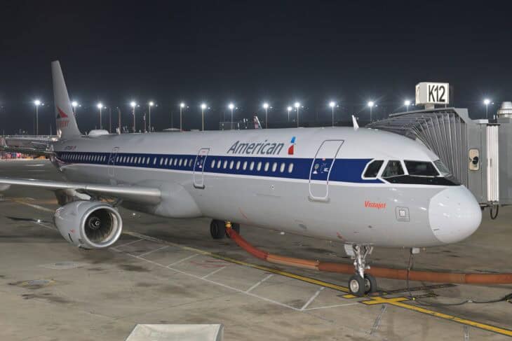 American Airlines Airbus A321 in retro livery at a Chicago O'Hare gate with the jet bridge attached at night