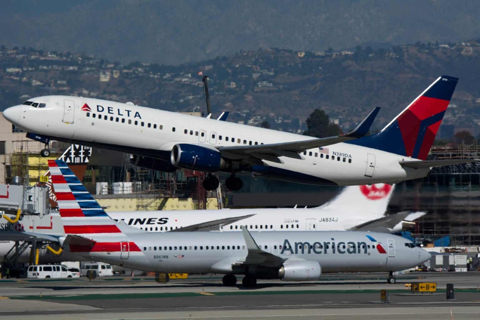 Delta Boeing 737 climbing out above an American Airlines 737 taxiing at Los Angeles International