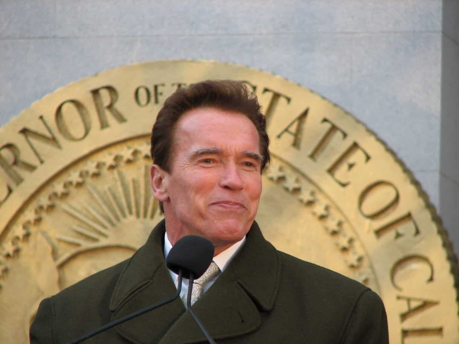 Arnold Schwarzenegger speaking at a podium in front of the Governor of the State of California seal