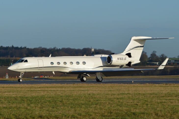 White Gulfstream V N162JC taxiing on a grass-edged airfield