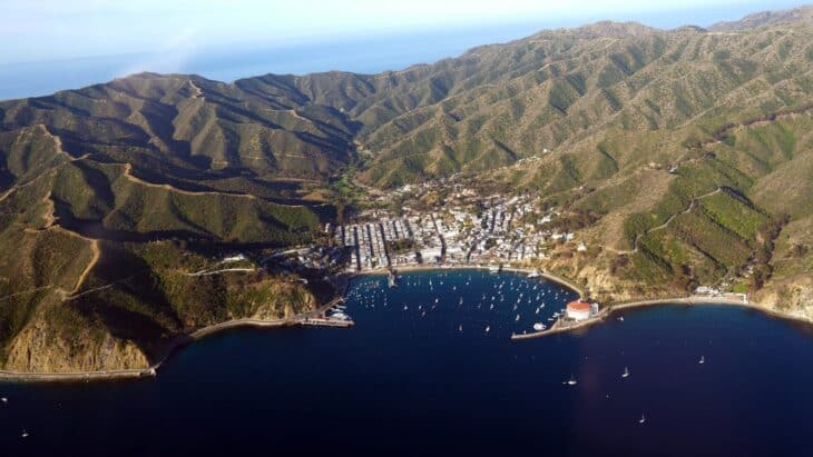 Aerial view of Avalon's harbor, boats and town on Santa Catalina Island, ringed by dry hills