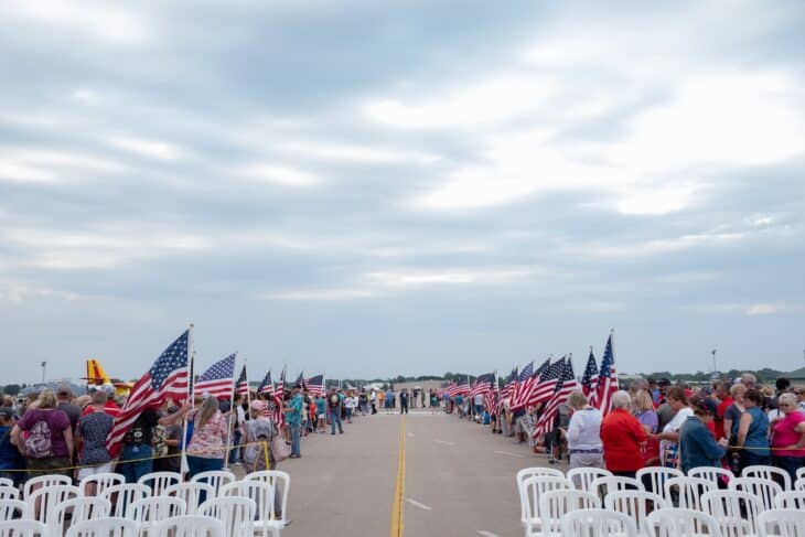 Crowds of visitors walking down a row of flags at EAA AirVenture Oshkosh