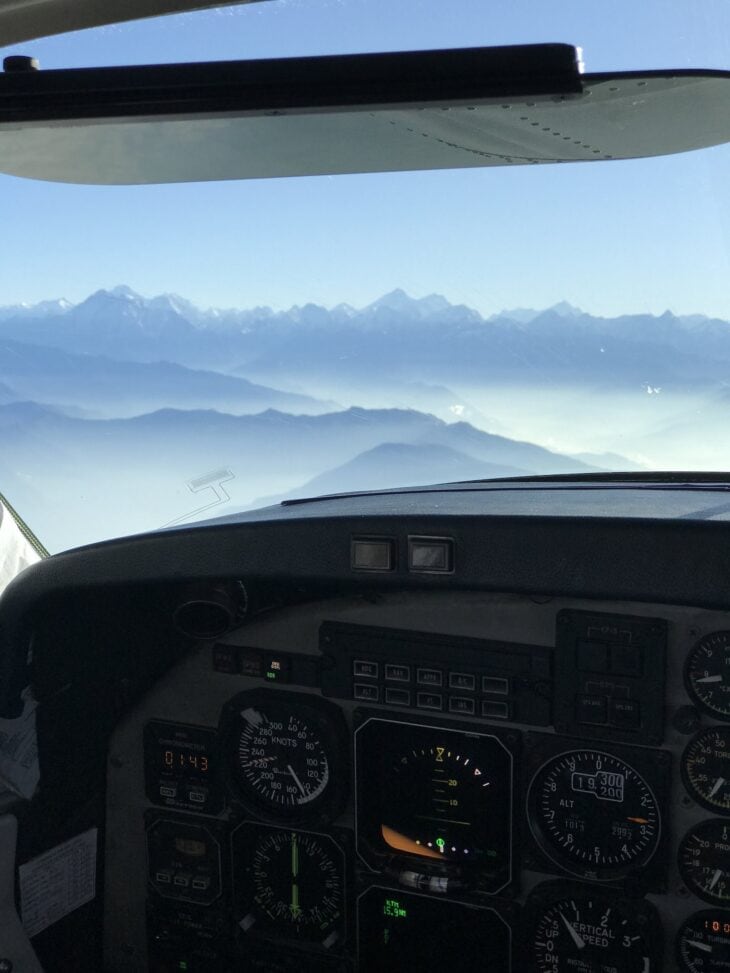View over mountains through a cockpit windscreen with instrument panel