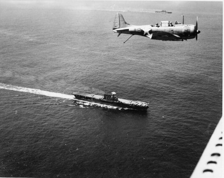Douglas SBD Dauntless dive bomber flying over the carrier USS Enterprise at sea