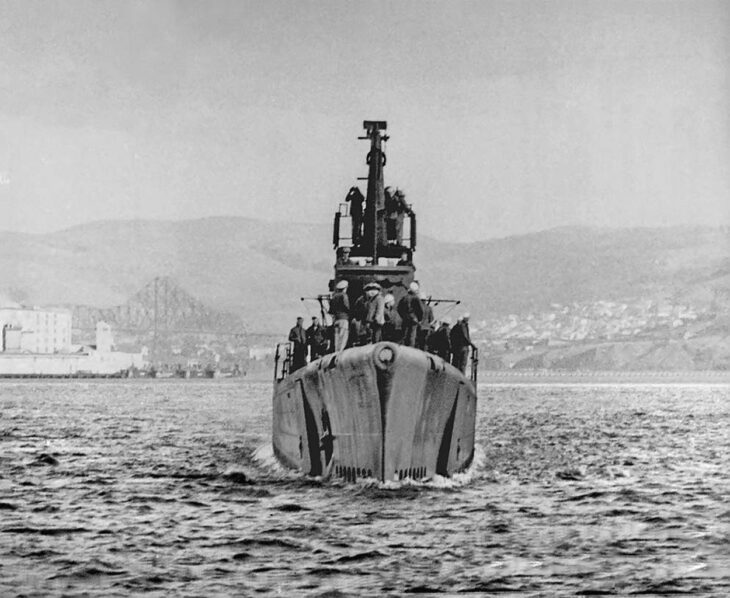 Bow-on view of the US Navy submarine USS Albacore (SS-218) running on the surface near a bridge