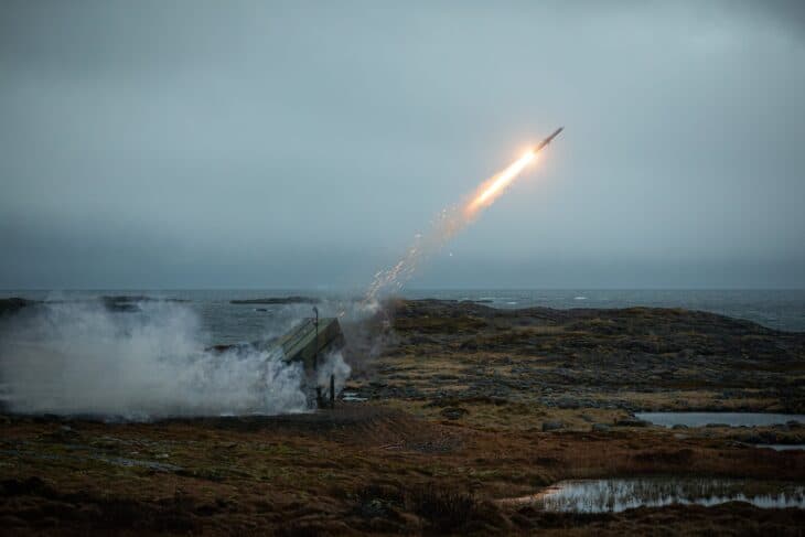 NASAMS missile climbing away from its launcher over a rocky Norwegian shoreline